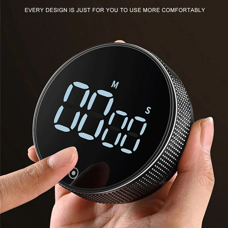 A hand holds a black magnetic kitchen timer with a digital display showing 00:00.