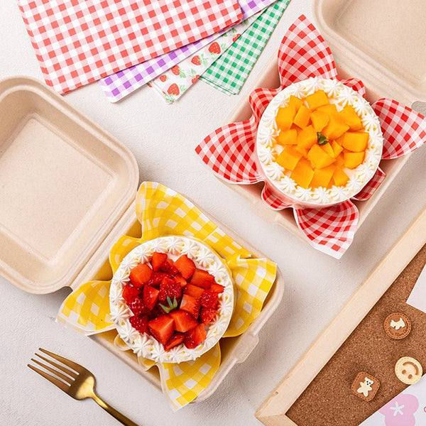 Ein Tablett mit fettbeständigen Lebensmittelverpackungen gefüllt mit frischem Obst, darunter Orangenscheiben und Erdbeeren.