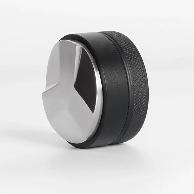 A black and silver precision espresso distribution tool with a rounded, disc-like shape.