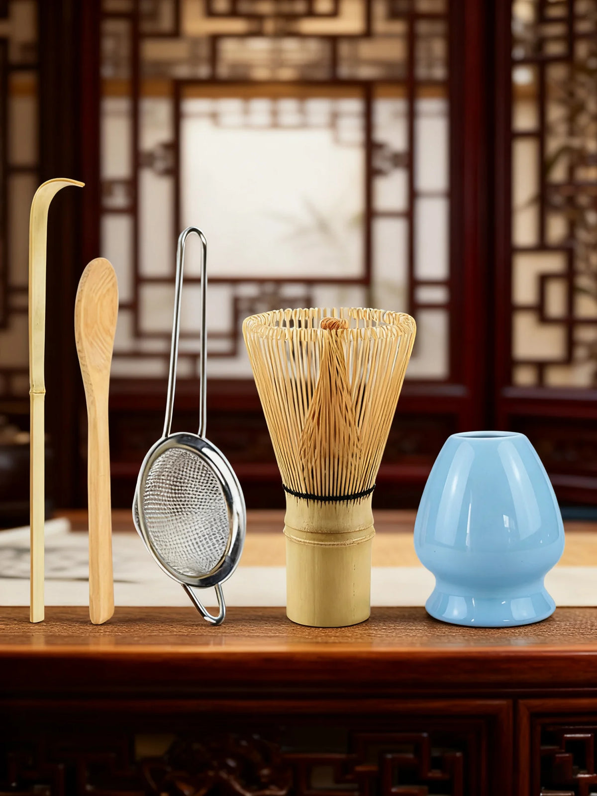 A set of bamboo matcha whisk tools including a bamboo ladle and a metal mesh whisk displayed on a wooden surface.