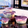 A set of stackable, clear purple airtight food storage containers with green and pink floral designs.