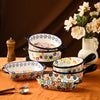 A colorful floral ceramic baking set with multiple bowls displayed on a wooden surface against a dark background.