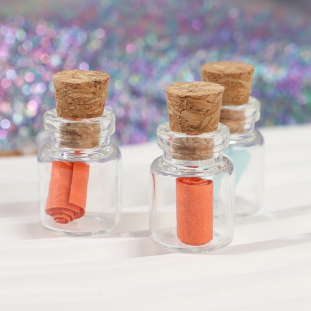 Klare Glasfläschchen mit Korkverschluss, die orangefarbige Substanz enthalten, auf einer weißen Oberfläche.