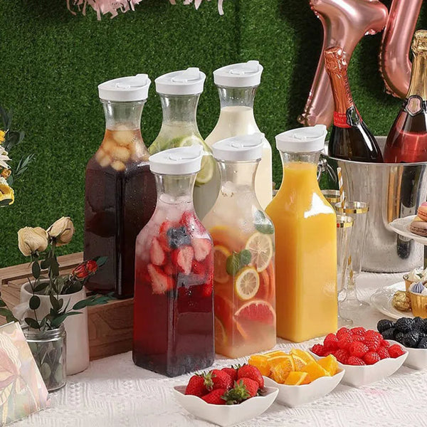 A glass bottle filled with red juice and a yellow bottle of juice next to a clear plastic water bottle.