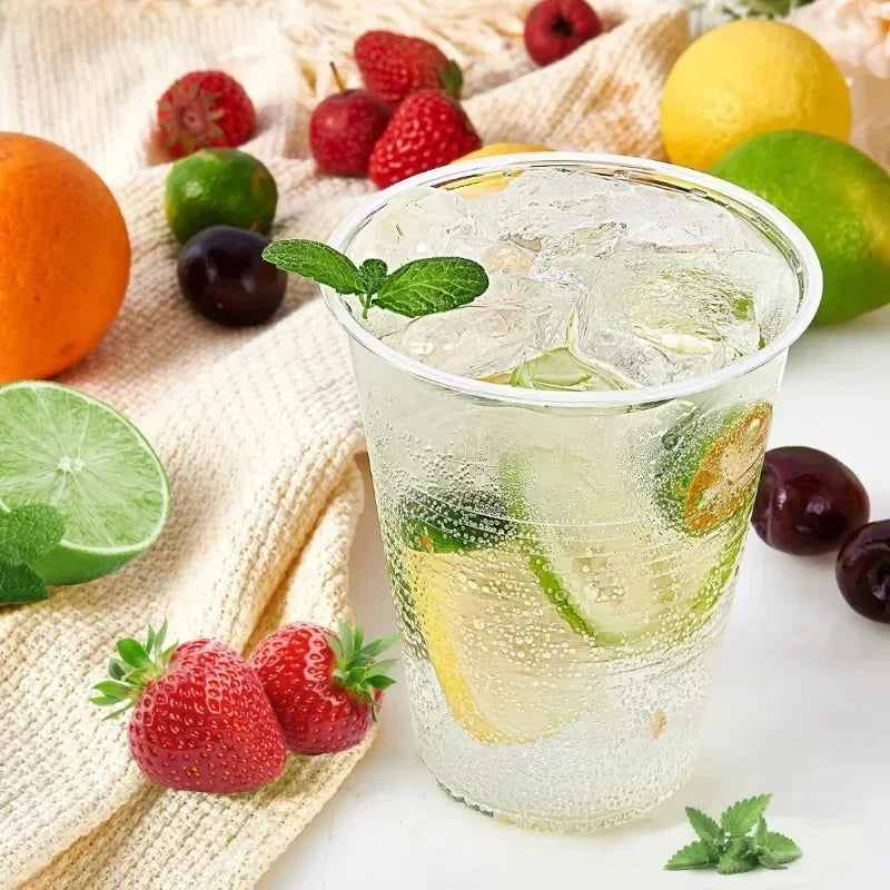 A glass of iced lemonade garnished with fresh fruit like strawberries, lemons, and limes, set on a beige cloth.