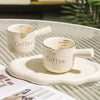 A white ceramic espresso coffee cup set with a matching saucer and a small informational card.