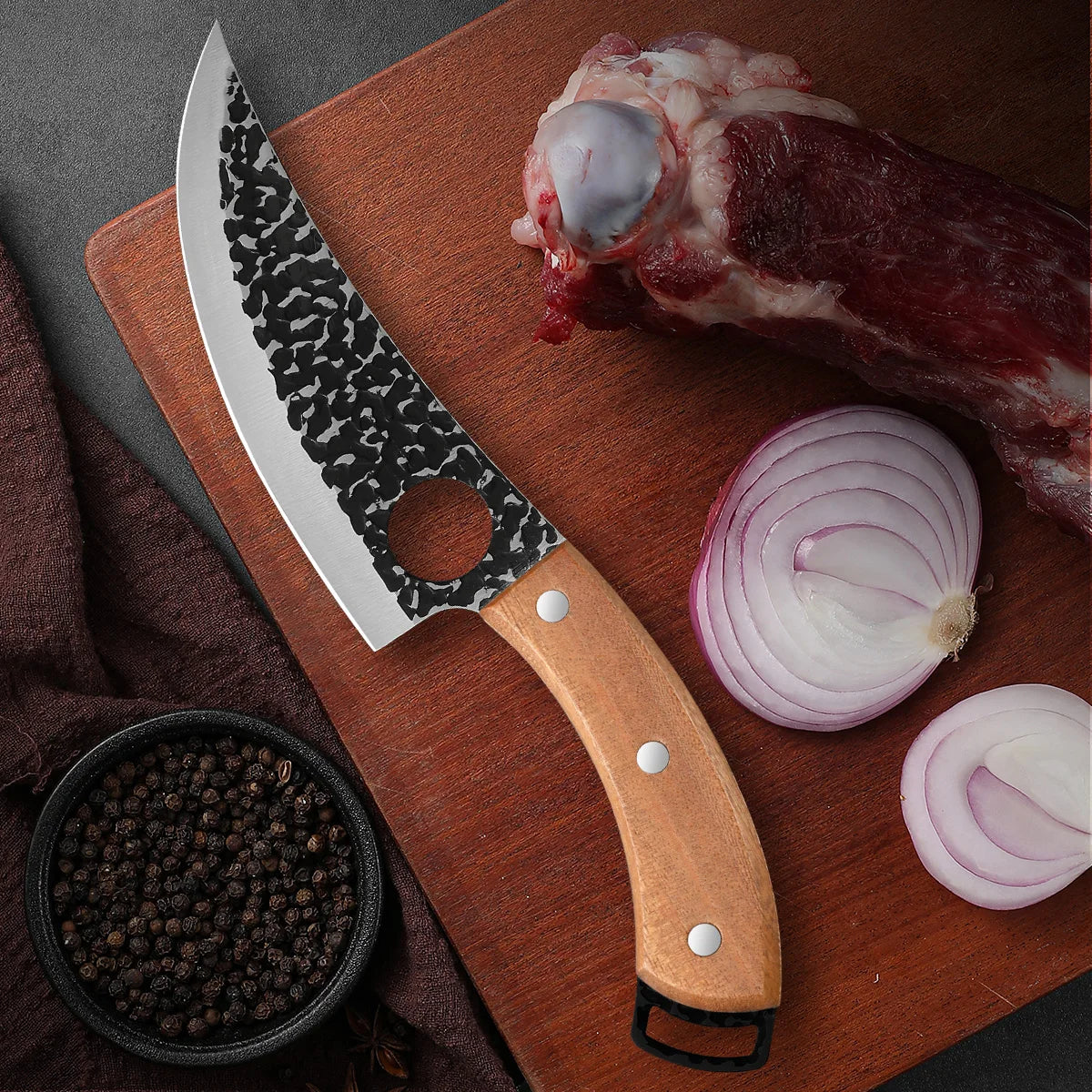 A forged kitchen knife set featuring a large blade and a wooden handle resting on a cutting board with raw meat and onions.