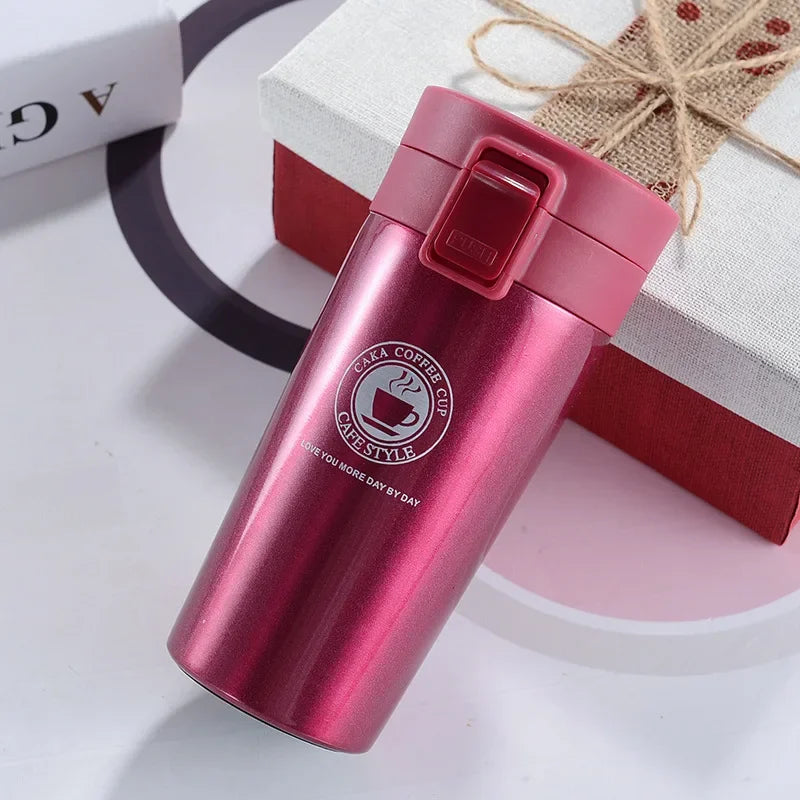 A pink double-walled stainless steel thermal travel mug with a red lid resting on a white surface.