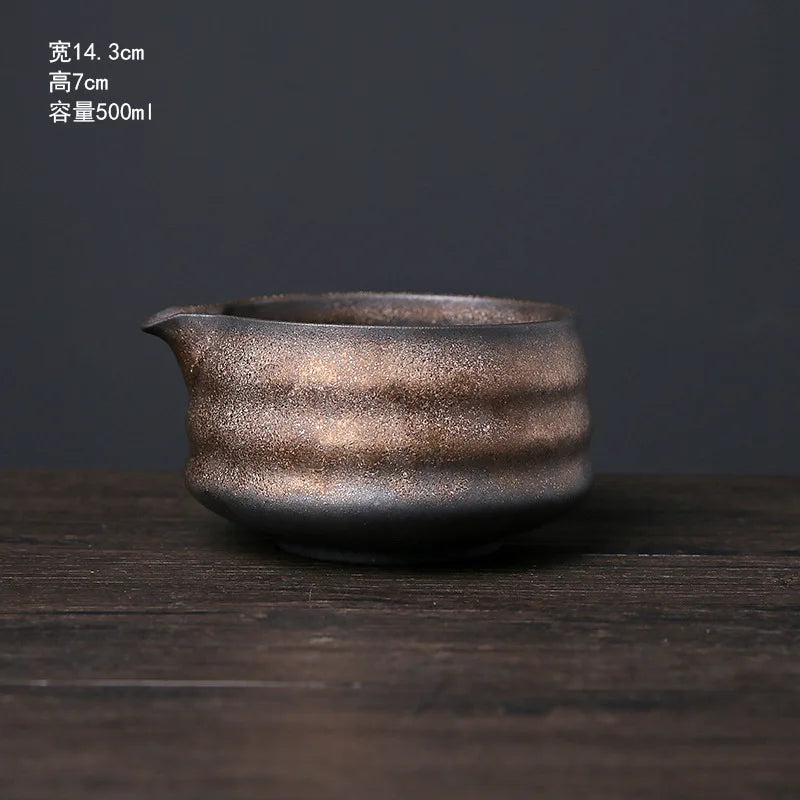 A dark, textured ceramic matcha whisk or bowl resting on a wooden surface.