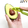 A hand holds an avocado half with a green slicer and corer tool, demonstrating its use.