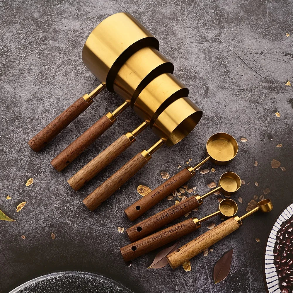A brass measuring set with wooden handles is displayed on a dark surface.