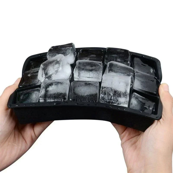 A hand holds a black silicone ice cube tray with a lid, filled with clear ice cubes.
