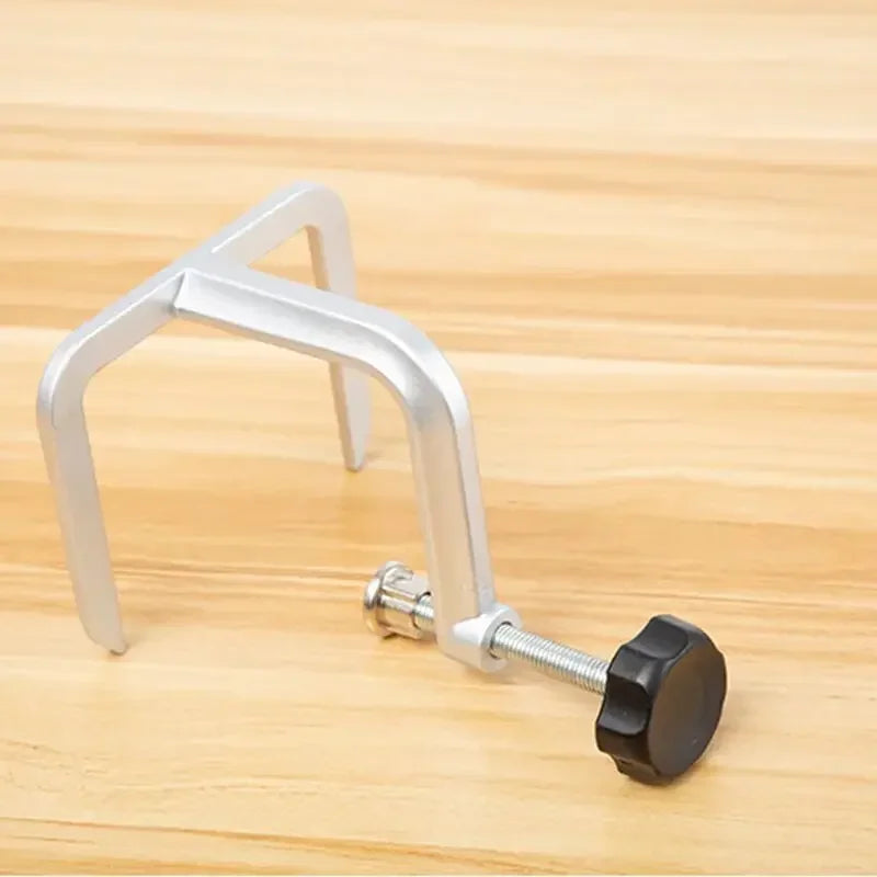 A silver diamond knife sharpener tool with a black handle resting on a wooden surface.