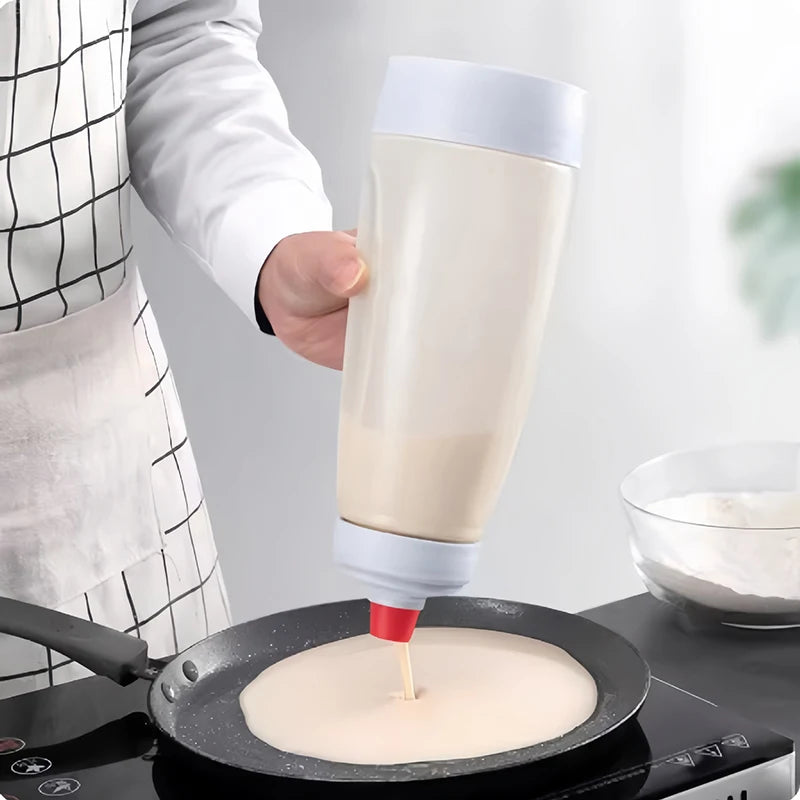 A hand is using a handheld batter mixer to blend batter in a frying pan.