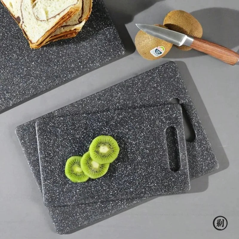 A set of dark gray marble texture cutting boards and a knife resting on them.