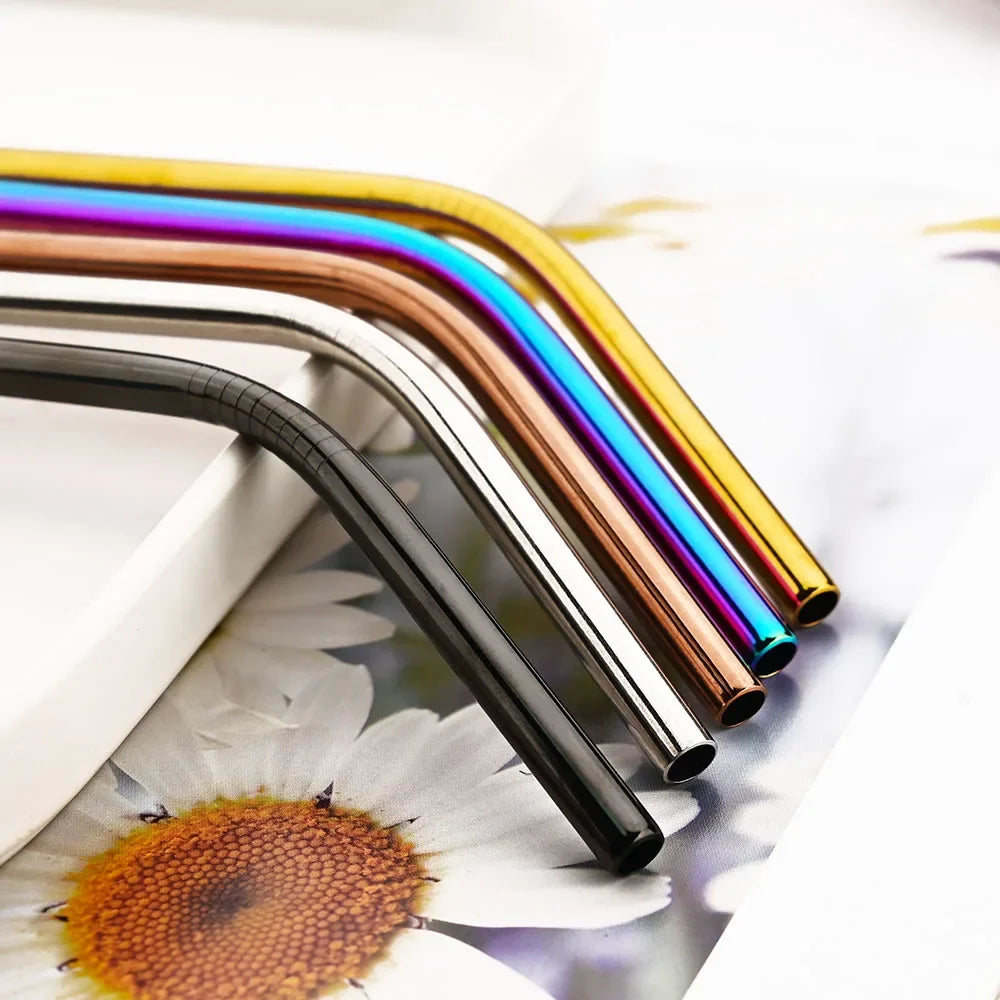 A close-up of a reusable metal straw set showing various colors like silver, copper, and iridescent blue on a white surface.
