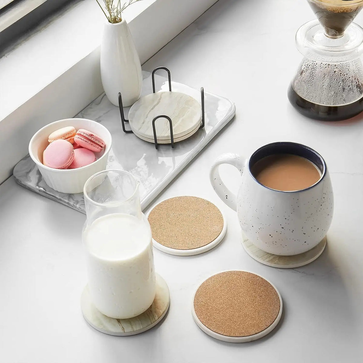 A set of marble style acrylic coasters and a ceramic mug with coffee on a white surface.