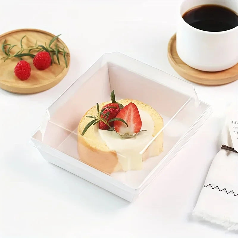 A clear square plastic box holds a slice of bread topped with cream cheese and fresh strawberries and mint leaves.