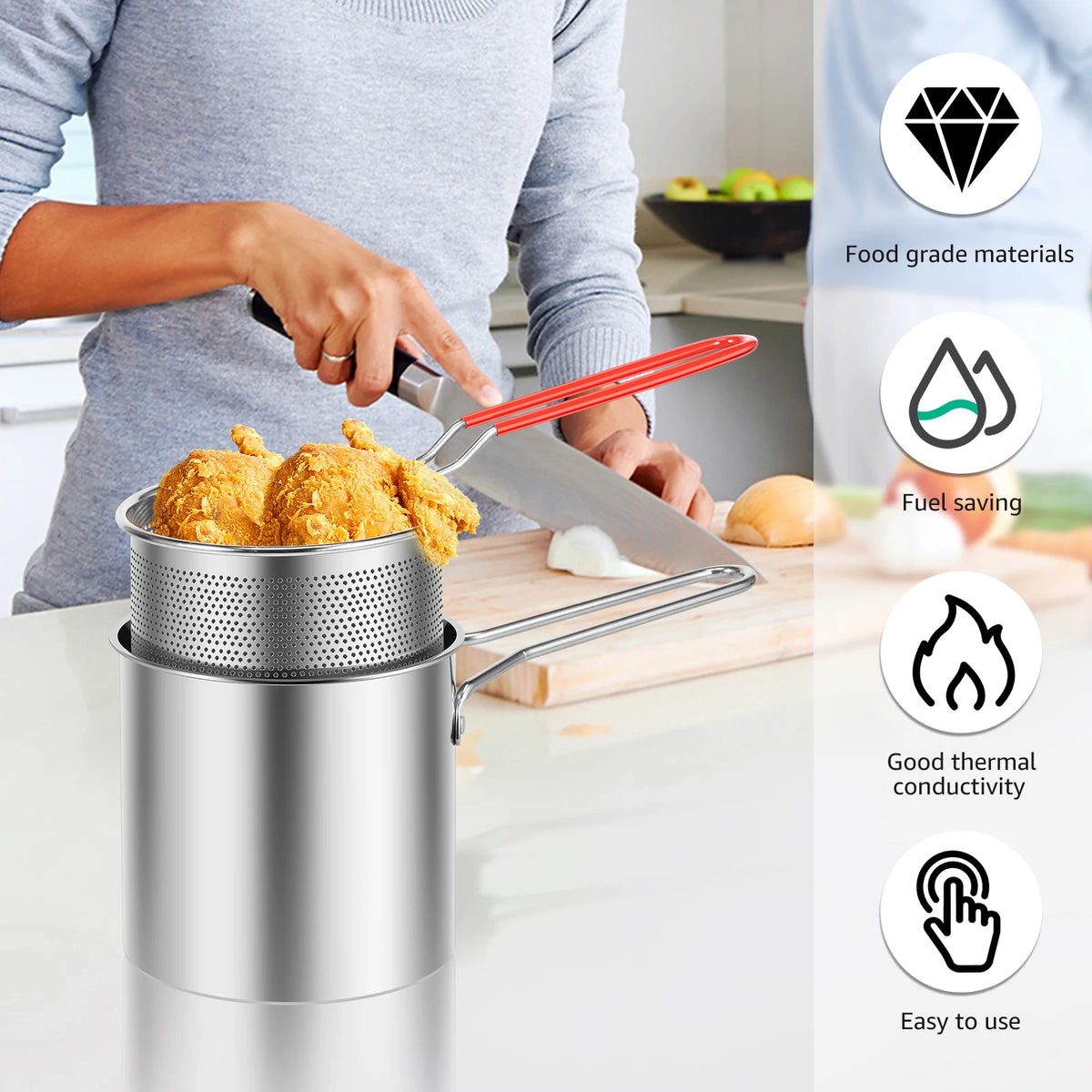 Stainless steel deep fryer pot with a strainer basket being used to fry food.