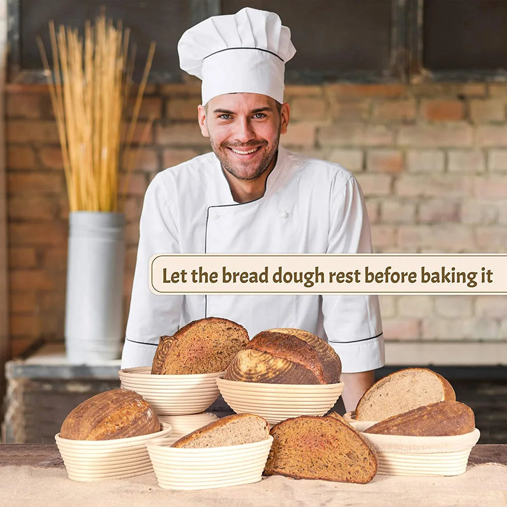 A smiling man in a chef's coat holds several loaves of bread dough in natural rattan proofing baskets.