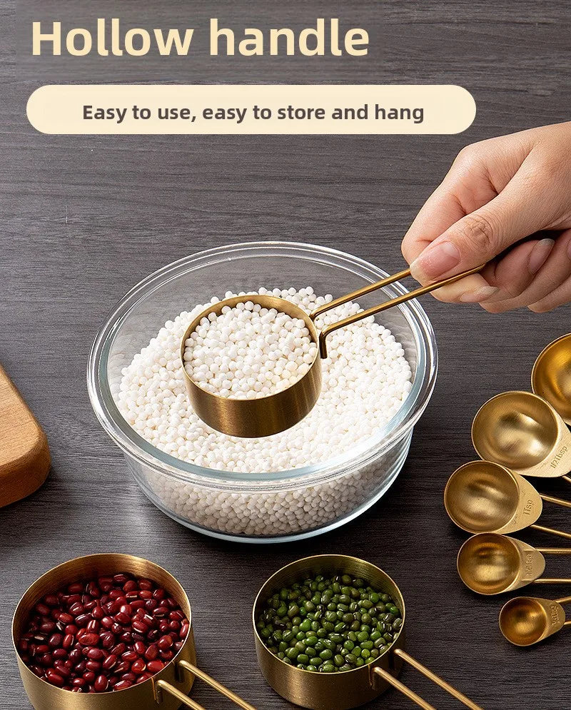 A hand is using a brass measuring spoon to scoop white seeds from a glass bowl, surrounded by other measuring spoons and seed