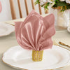 A stack of pink satin dinner napkins tied with gold thread, displayed on a white plate.