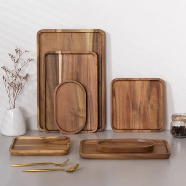 Ein Set aus natürlichem Akazienholz-Servierplatten und Schneidebrettern auf einer weißen Oberfläche.