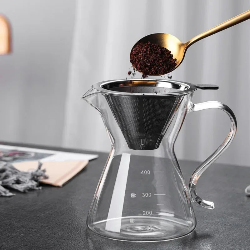 Une cuillère en or verse du marc de café foncé dans un filtre à café en verre transparent et en acier inoxydable.