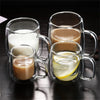 Two double wall insulated glass coffee cups with handles, one containing milk and the other containing a lemon-infused bevera