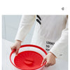Una mano sostiene una tapa de silicona roja y protector contra salpicaduras, demostrando su uso para la seguridad al cocinar 