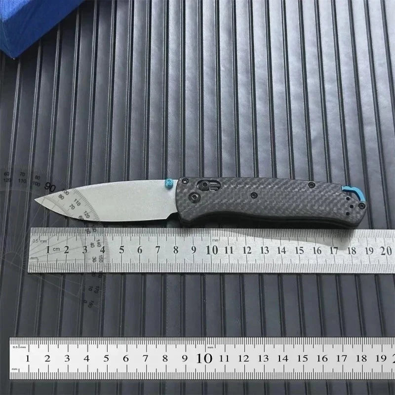 A silver utility knife with a black handle is shown resting on a measuring ruler.