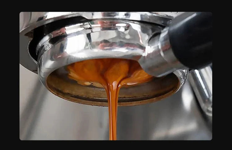 Un chorro de líquido ámbar oscuro gotea de una pantalla de café espresso de metal.