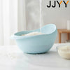 A light blue colander is shown with water dripping into it on a white surface.