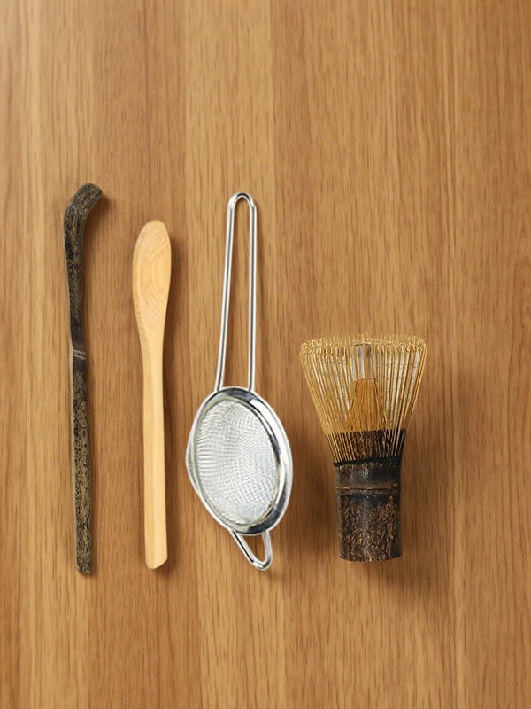 Set von vier Bambus-Tee-Rührwerkzeugen, einschließlich eines langen Stäbchens, Löffels und eines Maschensiebs.