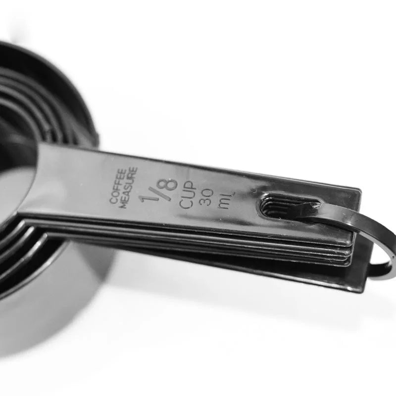 A close-up of a black precision kitchen measuring tools set with a 1/8 cup measure.