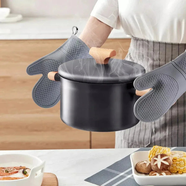 Eine Person trägt hitzebeständige Silikon-Ovenhandschuhe und hält einen dunklen Topf, um das Produkt zu demonstrieren.