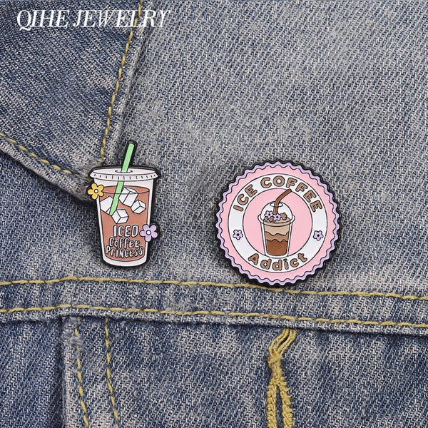 Email-Broche in Form einer Eiskaffeetasse mit Blumen-Detail auf Jeansstoff.