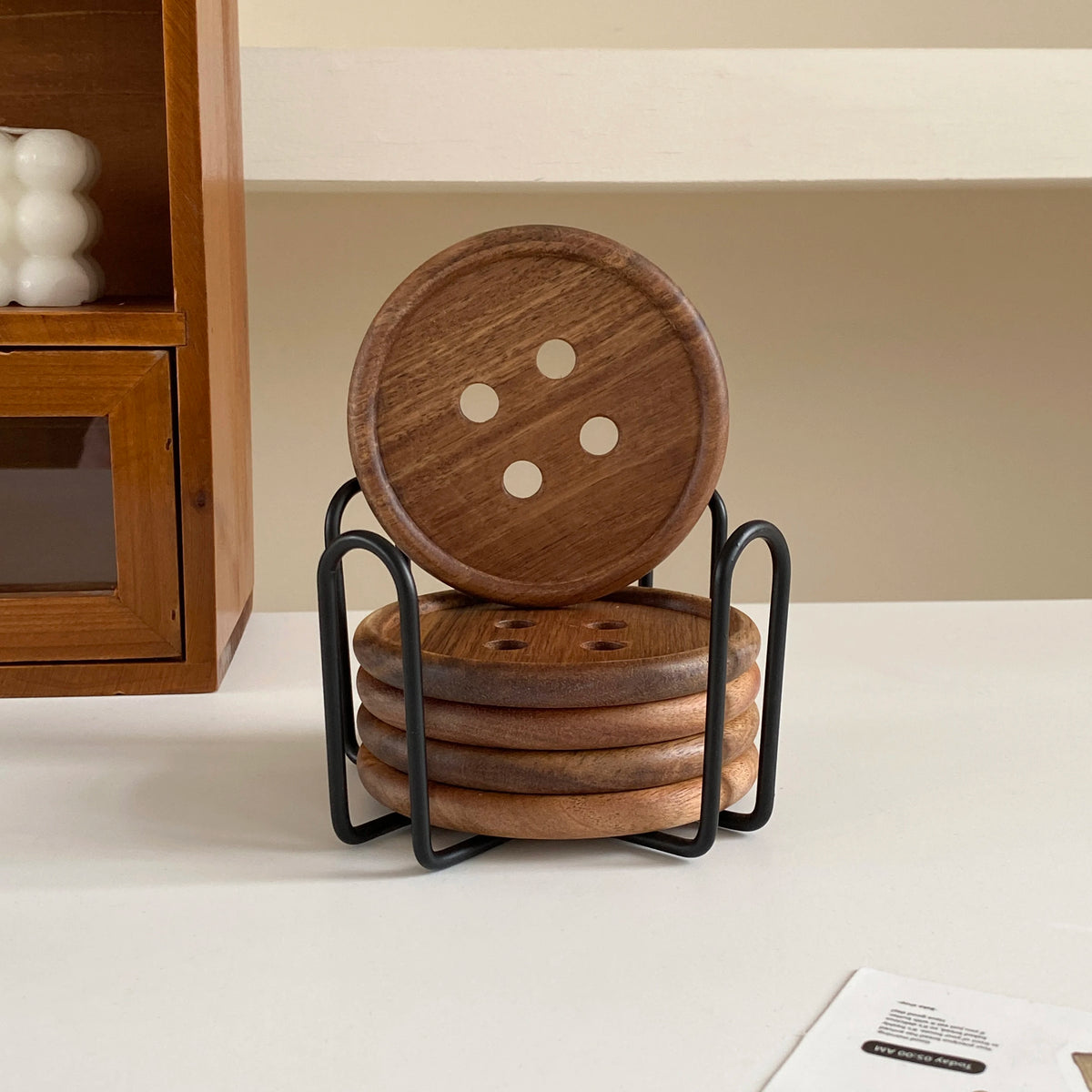 A stack of six round wooden coasters with an iron rack displayed on a white surface.