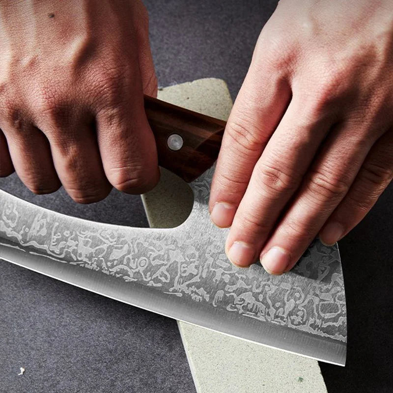 Hands holding a hand-forged stainless steel chef knife with a wooden handle