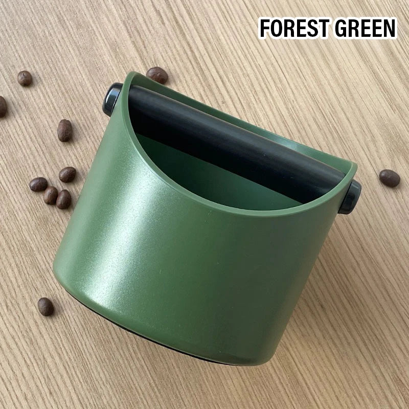 A forest green espresso knock box with a black lid resting on a light wooden surface.