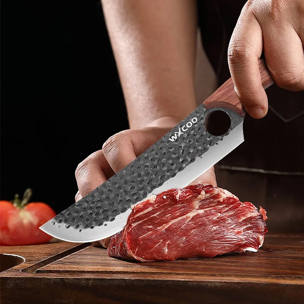 A hand is holding a professional stainless steel chef knife with a protective sheath, positioned above a cut piece of raw red