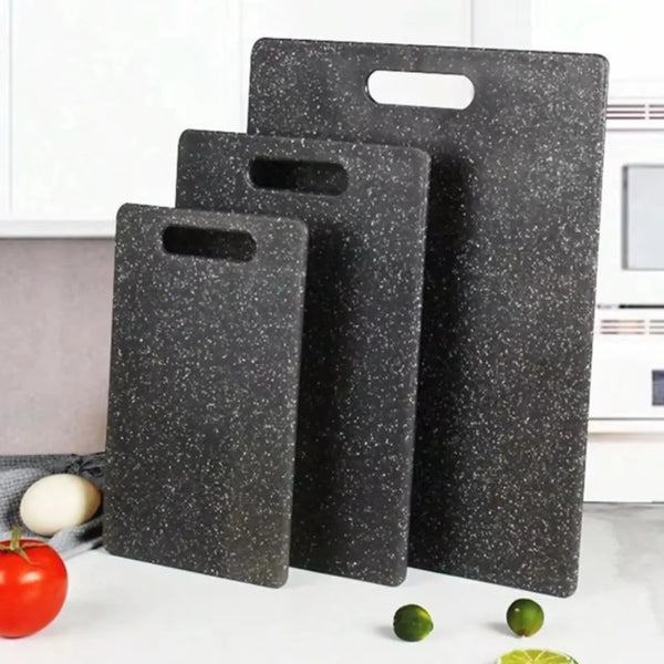 Drei schwarze Marmor-Cuttingboards mit rutschfester Oberfläche werden auf einer weißen Fläche mit frischen Lebensmitteln präs