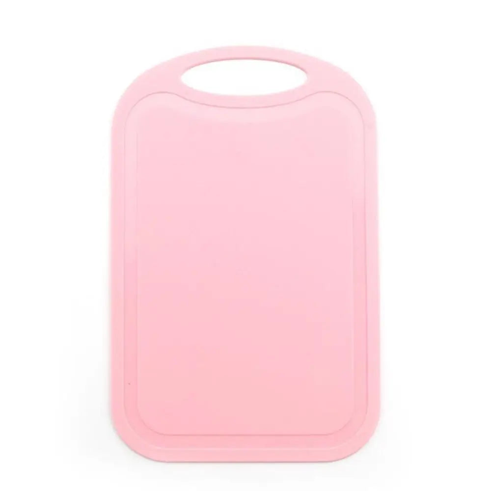 A pink non-slip plastic cutting board with a hanging handle.