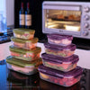 Stack of purple and green airtight food storage containers on a black surface next to a microwave oven.