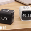 A black productivity cube timer displaying 99:58 is shown on a wooden surface.