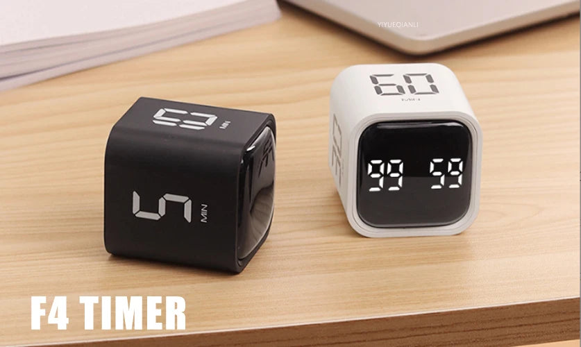 A black productivity cube timer displaying 99:58 is shown on a wooden surface.