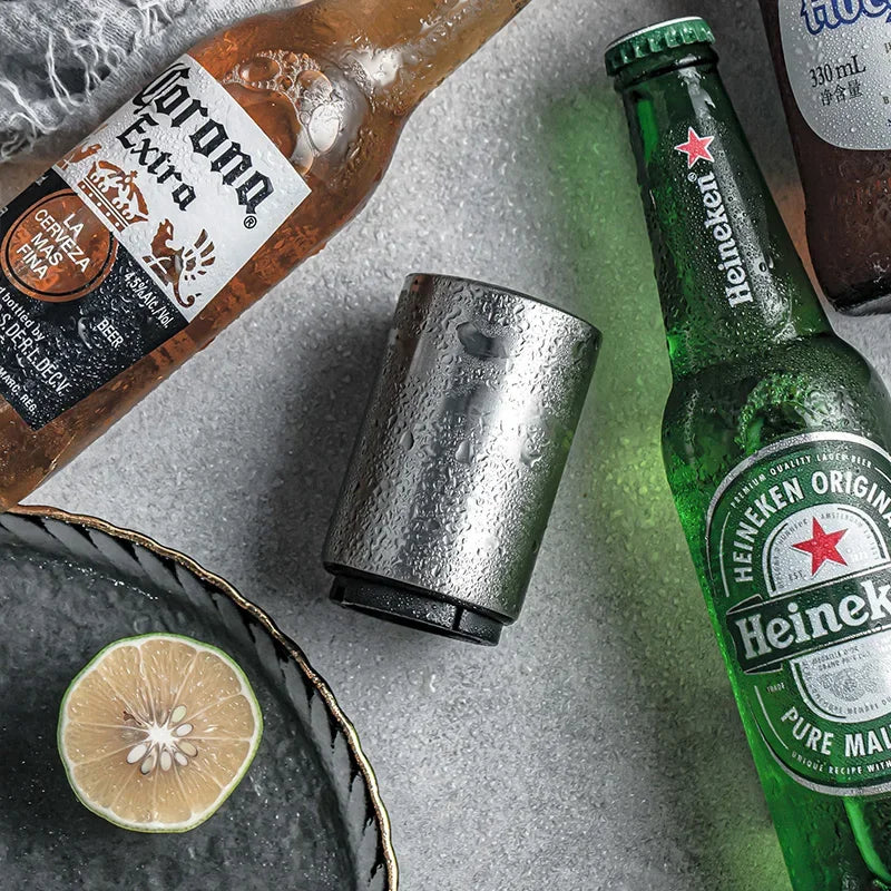 A stainless steel automatic beer bottle opener next to a Heineken beer bottle and a slice of lemon.