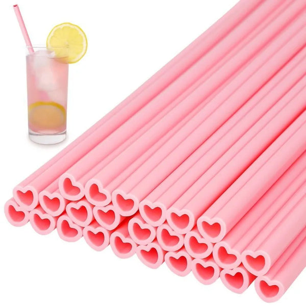 Ein Bund rosa herzförmiger Strohhalme und ein Glas mit Zitronenscheibe.