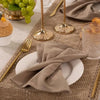 A set of reusable cotton cloth napkins and gold-toned cutlery arranged on a burlap table setting.