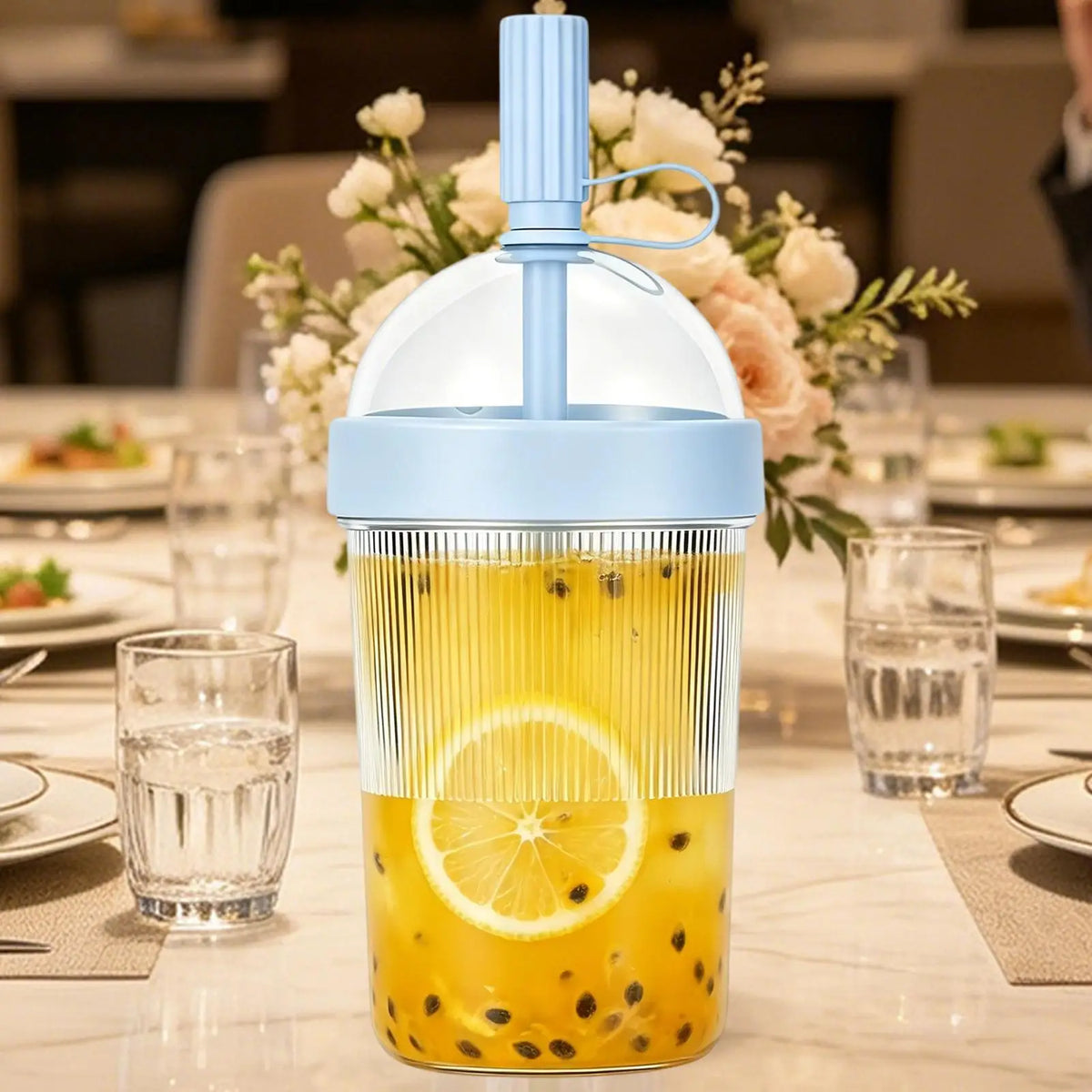 A reusable tumbler coffee cup filled with iced tea and fruit, featuring a light blue straw lid.